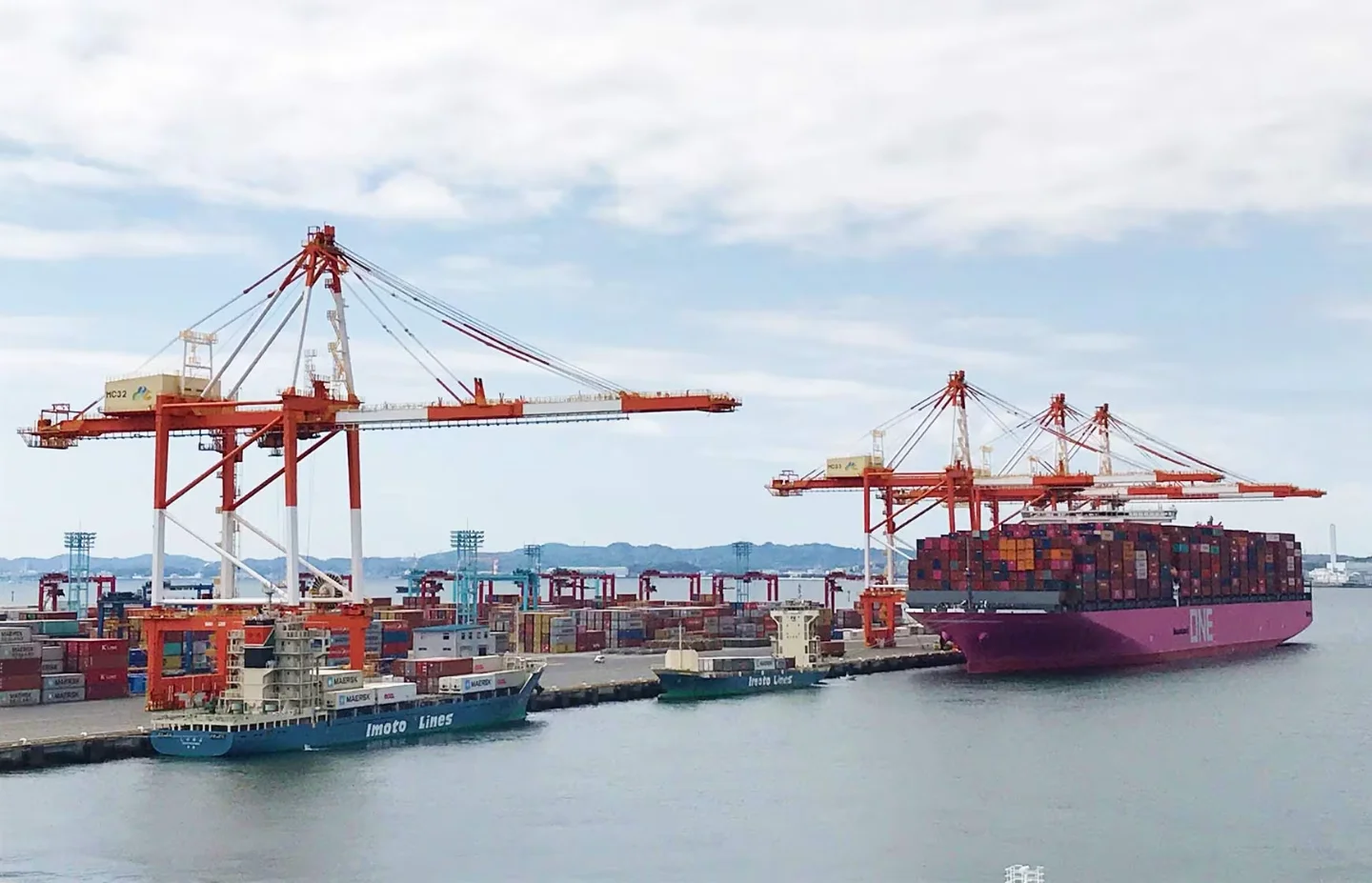Red dockside cranes and container vessels at the port of Yokohama, Japan.